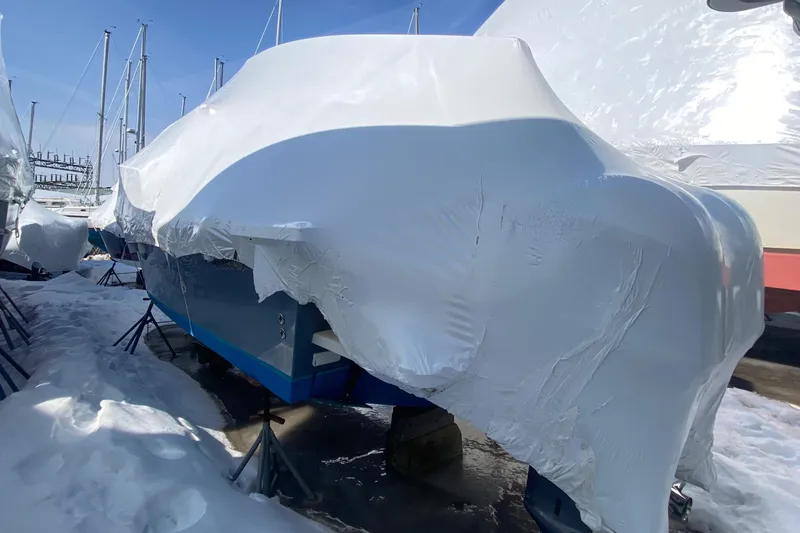 Slide: The Image of 2018 Parker 2530 Extended Cabin boat covered in protective wrap, stored outdoors in winter. - 1