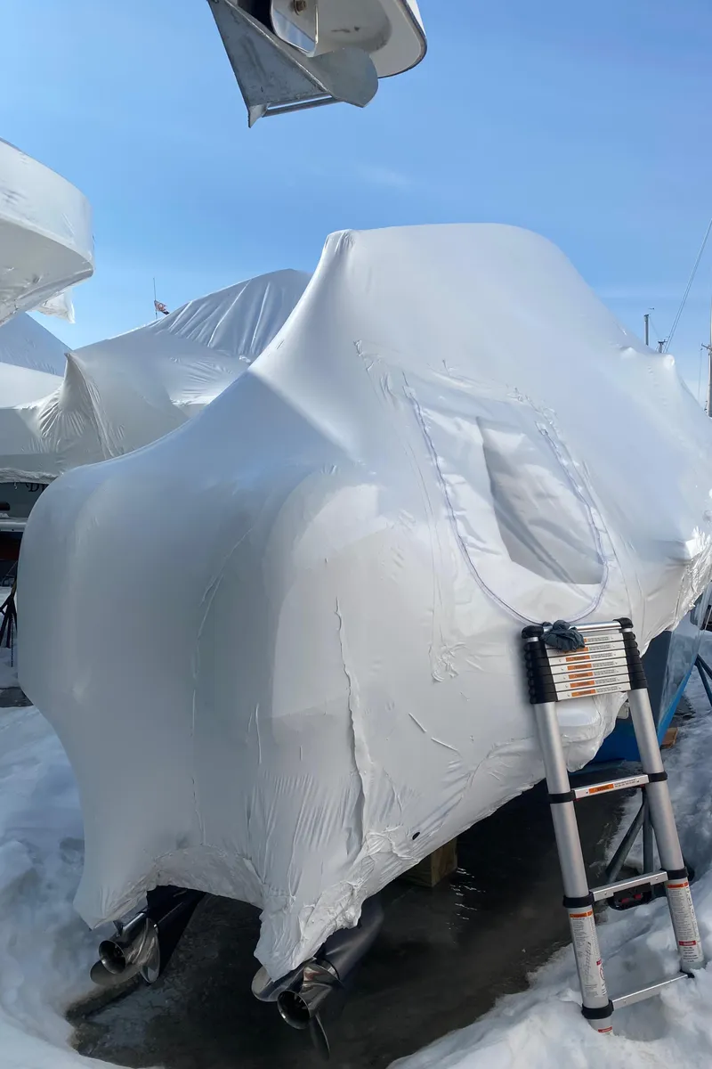 Slide: The Image of 2018 Parker 2530 Extended Cabin boat covered in protective wrap, with a ladder nearby. - 2