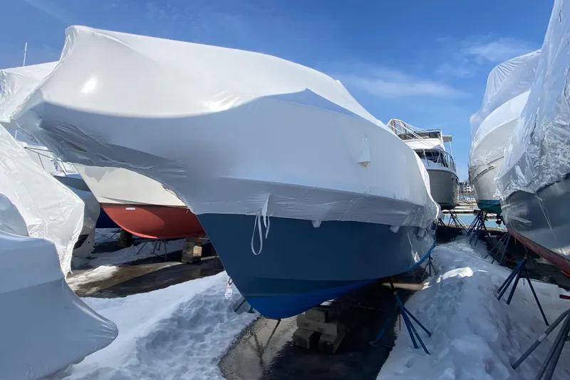 Slide: The Image of 2018 Parker 2530 Extended Cabin boat covered in protective wrap, stored outdoors in snowy conditions. - 3