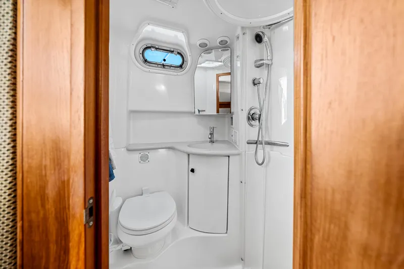 Slide: The Image of Compact bathroom in a 2002 Pursuit 3800 Express boat, featuring a toilet, sink, and shower. - 36