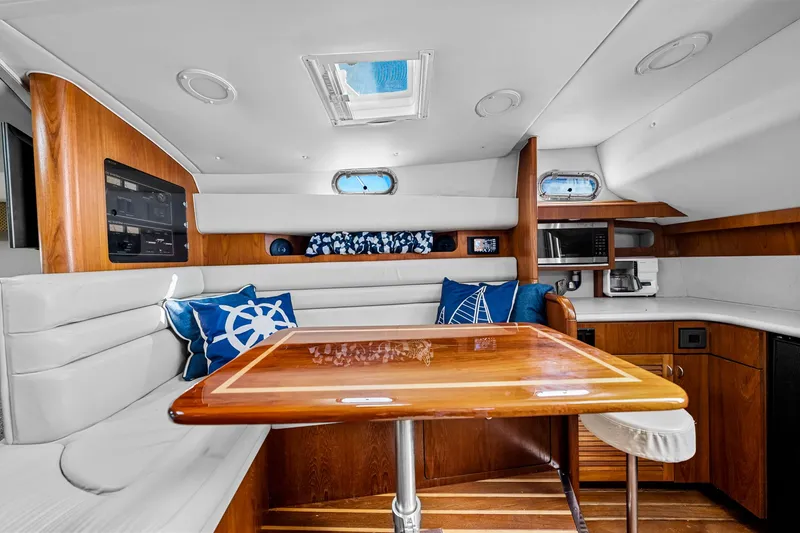 Slide: The Image of Interior of 2002 Pursuit 3800 Express yacht with wooden table and nautical-themed cushions. - 38