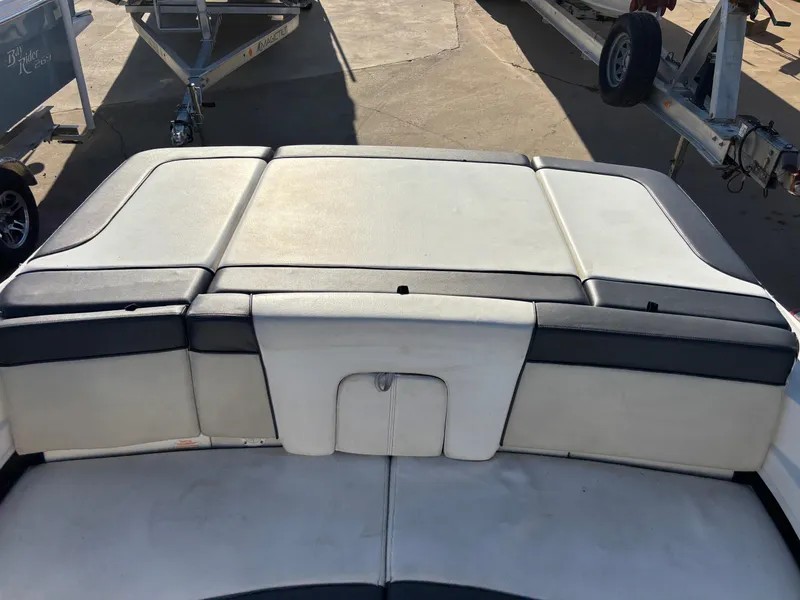 Slide: The Image of 2014 Sea Ray 205 Sport boat interior with cushioned seating and trailer in background. - 25