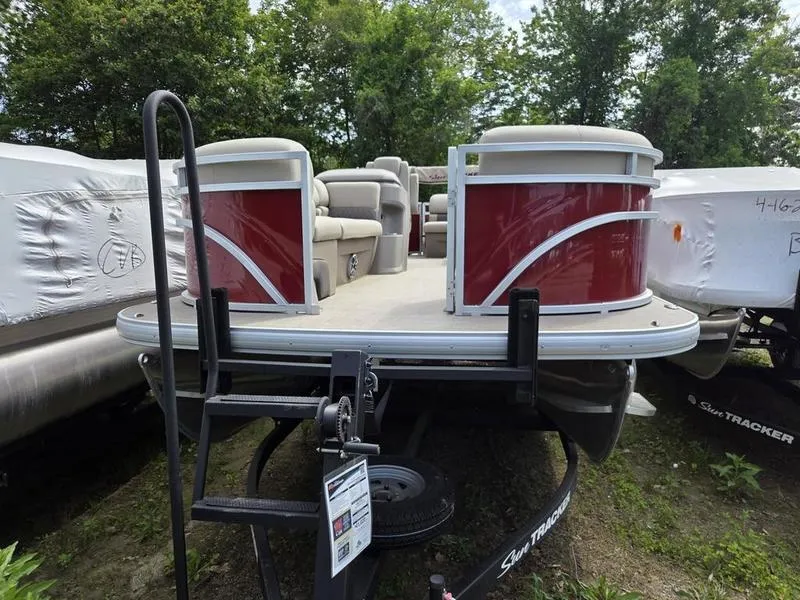 Slide: The Image of 2025 Sun Tracker PB 20 DLX pontoon boat with red accents, parked on a trailer. - 4