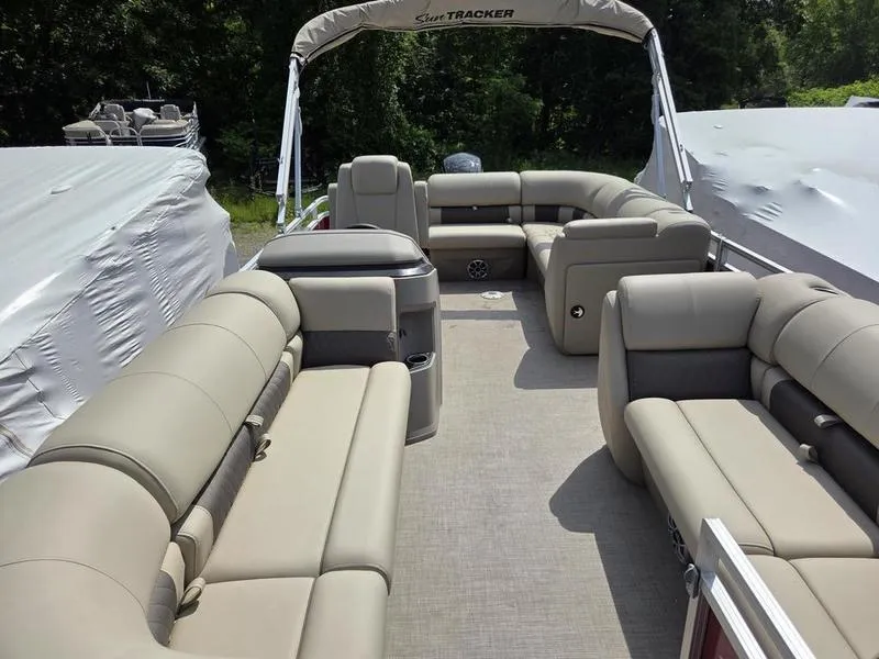 Slide: The Image of 2025 Sun Tracker PB 20 DLX pontoon boat with spacious seating and canopy, parked outdoors. - 7