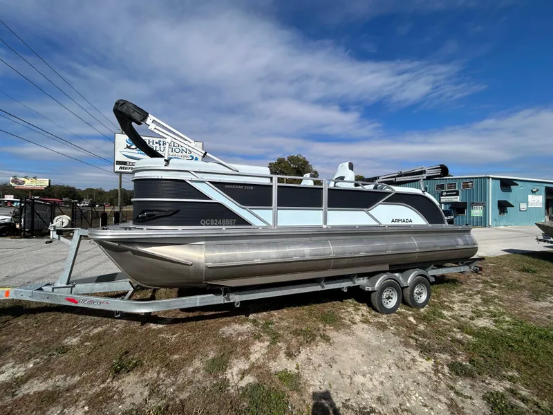The Image of 2025 Armada Drakkar K-23SB 3T pontoon boat on trailer, parked outdoors. - 1