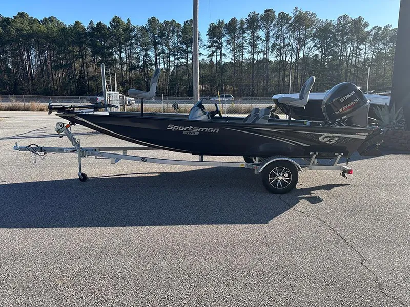 Slide: The Image of 2025 G3 Sportsman 1710 boat on trailer, parked outdoors, with trees in background. - 2