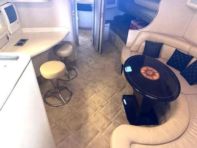 Slide: The Image of Interior of 1996 Sea Ray 400 EXPRESS yacht with seating, table, and stools. - 11