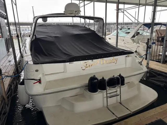 Slide: The Image of 1996 Sea Ray 400 EXPRESS boat docked, covered with a black tarp, in a marina. - 23