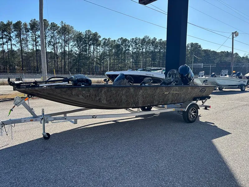 The Image of 2025 G3 Sportsman 1810 boat on trailer, parked outdoors, with trees in the background. - 1