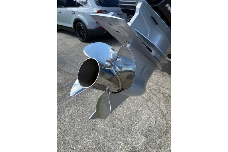 Slide: The Image of 2025 Bennington R Line boat propeller, shiny chrome finish, parked car in background. - 12