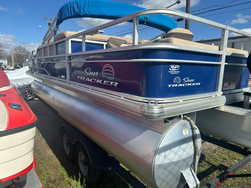 Slide: The Image of 2017 Sun Tracker Fishin' Barge 22 DLX pontoon boat with blue exterior on trailer. - 2