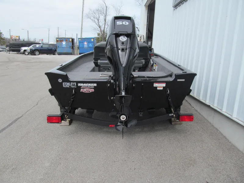 Slide: The Image of 2024 Tracker Super Guide V-16 SC boat, rear view with motor, parked outdoors. - 4