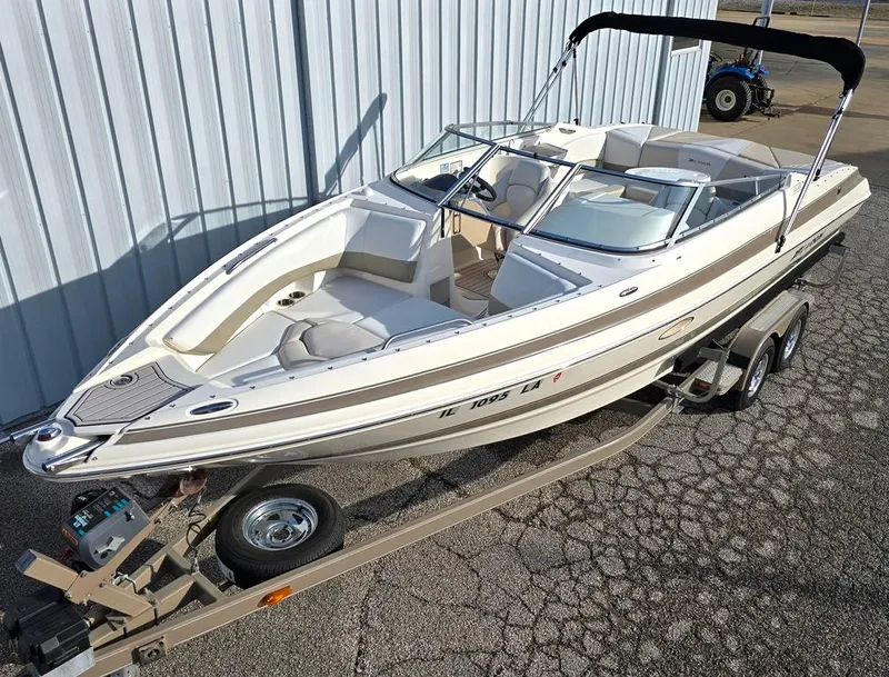 Slide: The Image of 2006 Larson LXI 268 BR boat on trailer, parked outdoors near a metal building. - 0