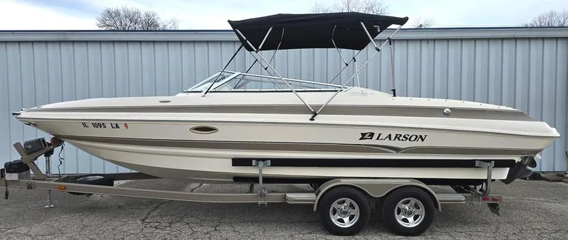 Slide: The Image of 2006 Larson LXI 268 BR boat on trailer with black canopy, parked outdoors. - 11