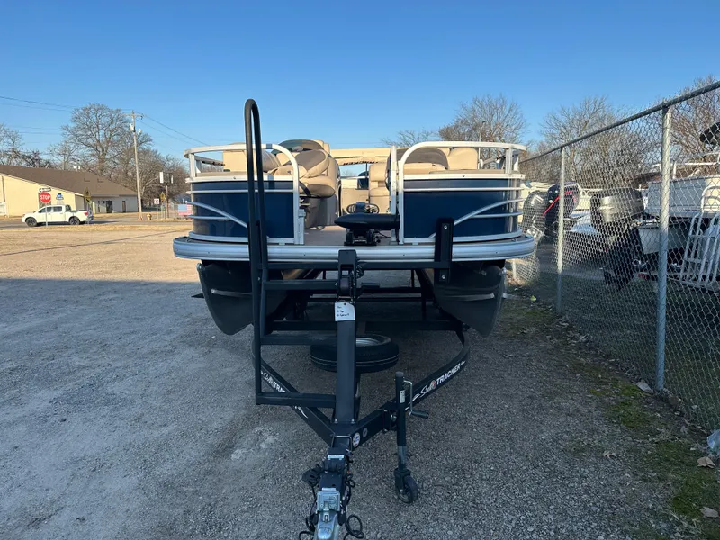 Slide: The Image of 2023 Sun Tracker Fishin' Barge 20 DLX pontoon boat on trailer, parked outdoors. - 2