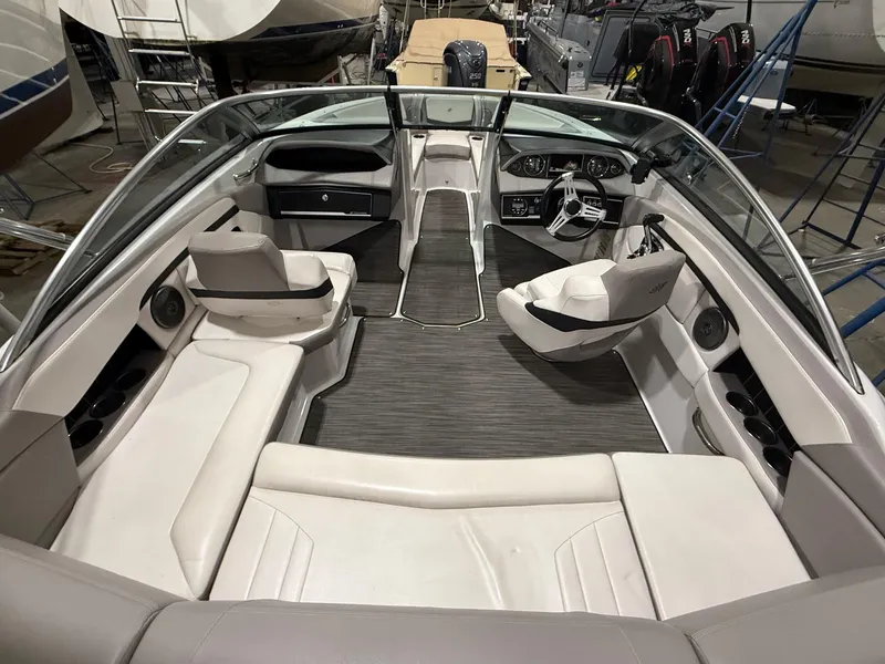 Slide: The Image of 2018 Four Winns H210 boat interior with seating and steering wheel in a showroom. - 10