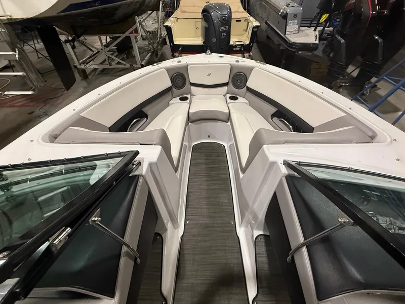 Slide: The Image of 2018 Four Winns H210 boat interior with seating and speakers in a showroom. - 18