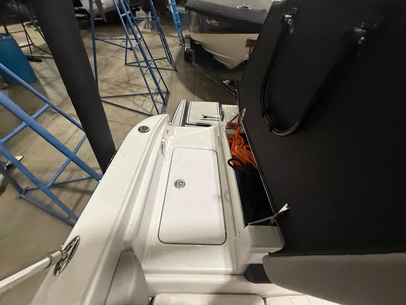 Slide: The Image of 2018 Four Winns H210 boat interior with open storage compartment in a garage setting. - 23