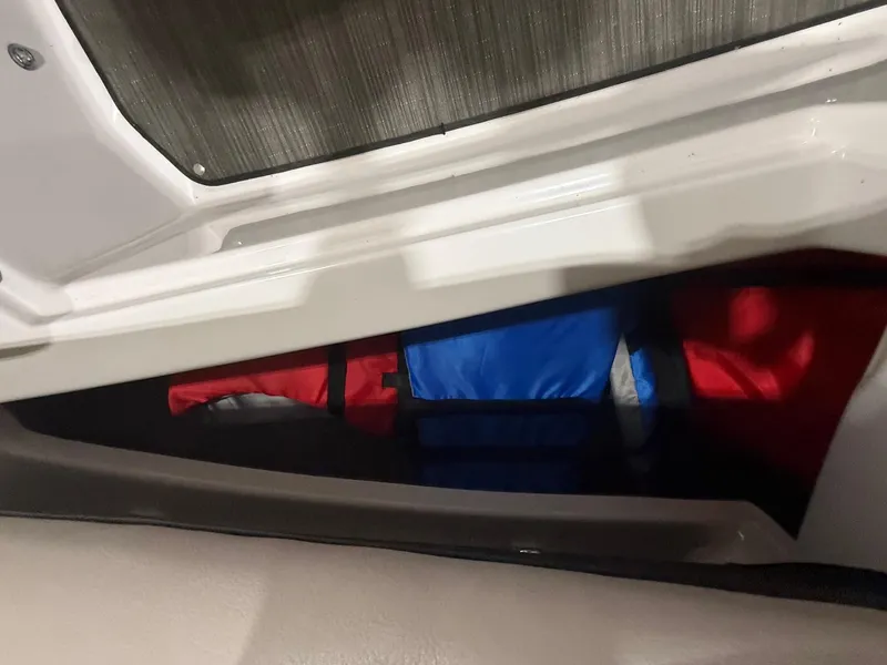 Slide: The Image of Storage compartment in 2018 Four Winns H210 boat with colorful life jackets. - 28