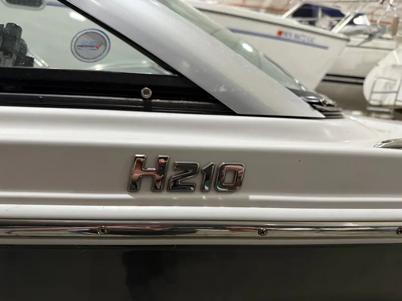 Slide: The Image of 2018 Four Winns H210 boat emblem close-up in a marina setting. - 30