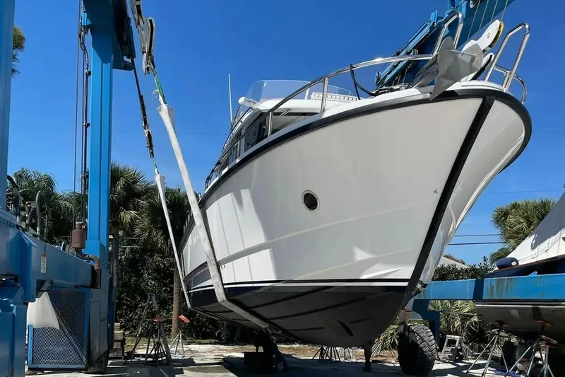 Slide: The Image of 2015 Sargo 36 Fly boat in dry dock, lifted by crane under clear blue sky. - 4