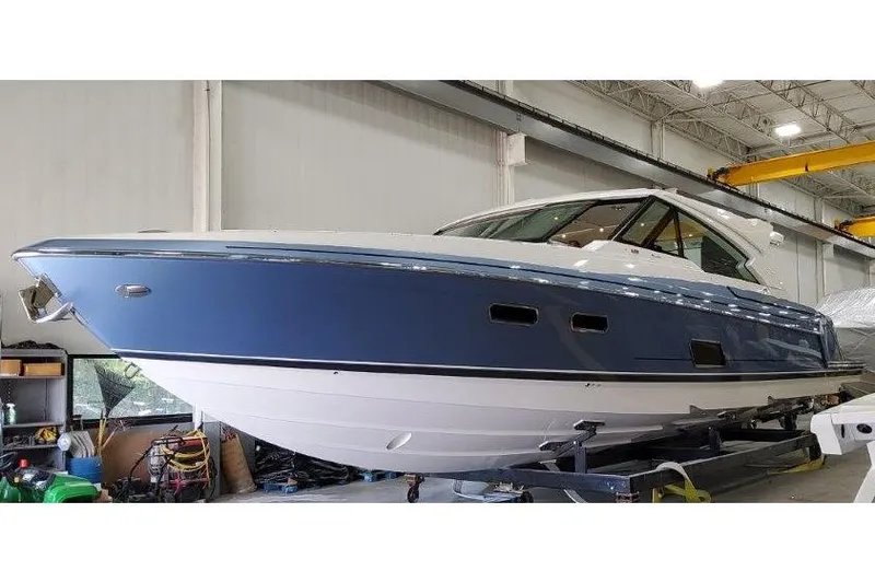 Slide: The Image of 2023 Formula 500 Super Sport Crossover boat in a showroom, blue and white exterior. - 35