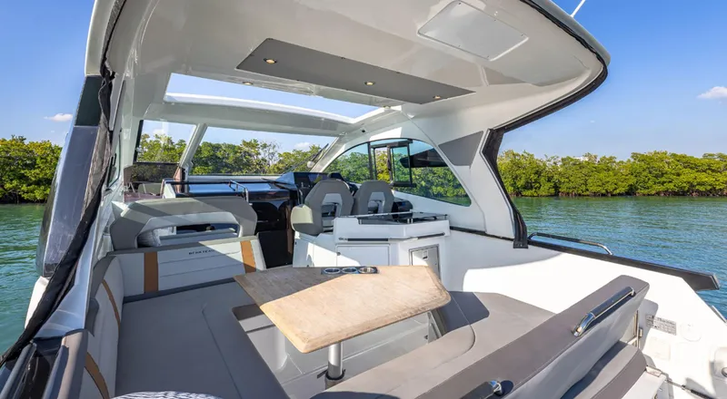 Slide: The Image of 2021 Beneteau Gran Turismo 32 yacht interior with seating and table, surrounded by water and greenery. - 12