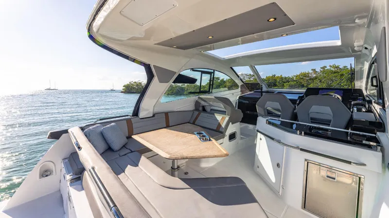Slide: The Image of 2021 Beneteau Gran Turismo 32 yacht interior with seating and table, overlooking serene waters. - 13