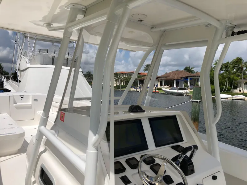 Slide: The Image of 2008 Intrepid 370 boat cockpit with steering wheel and navigation screens, docked by waterfront homes. - 23