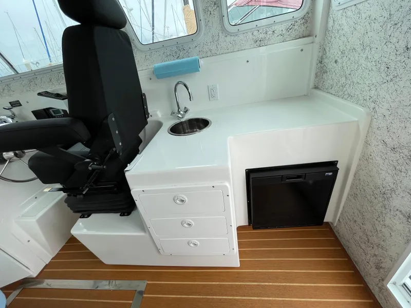 Slide: The Image of 2016 Farallon 3200 Explorer interior with captain's chair, sink, and mini fridge. - 22
