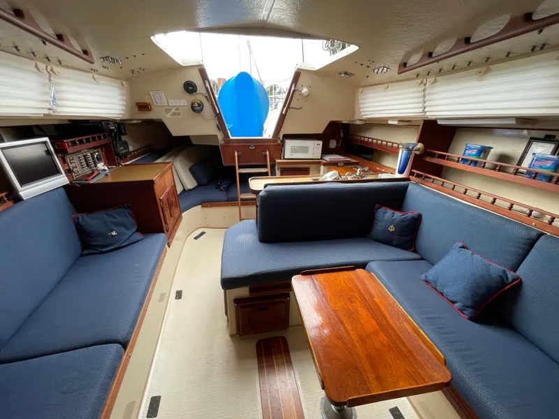 Slide: The Image of Interior of 1984 Catalina 30 sailboat with blue seating and wooden table. - 12
