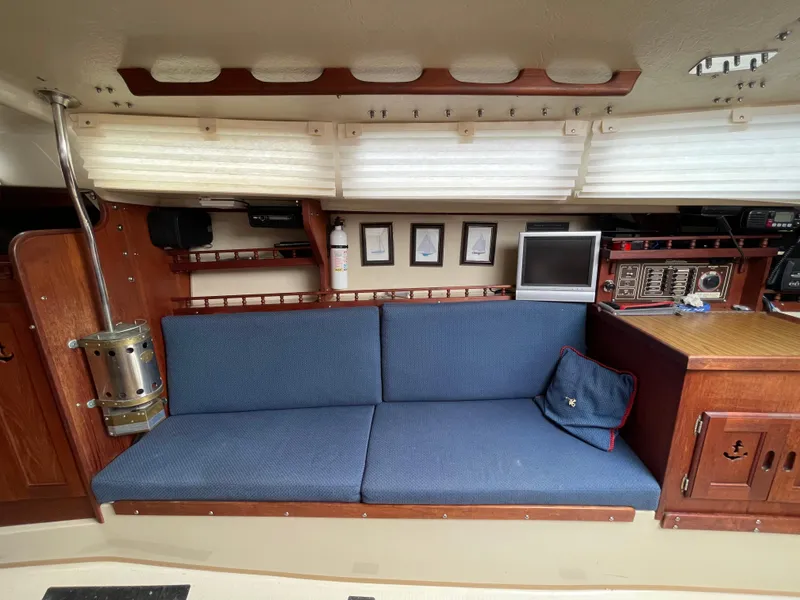 Slide: The Image of Interior of 1984 Catalina 30 sailboat with blue cushioned seating and wooden cabinetry. - 8