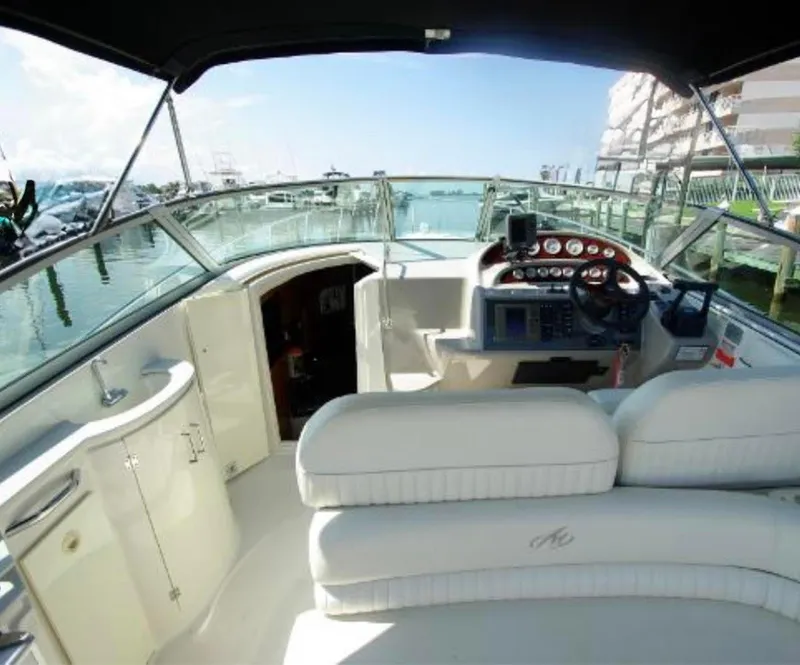 Slide: The Image of 2004 Monterey 322 Cruiser interior with helm, white seating, and marina view. - 10