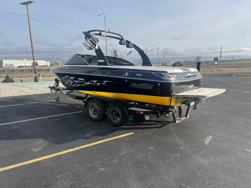 Slide: The Image of 2007 Malibu WVLX boat on trailer in parking lot, black and yellow design. - 7