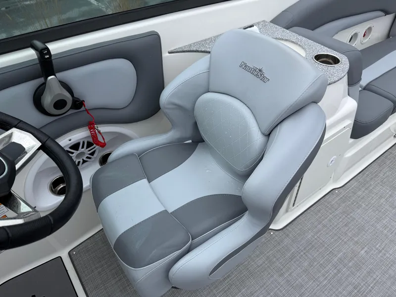 Slide: The Image of 2024 NauticStar 243 DC Deck boat interior with plush gray seating and modern controls. - 17