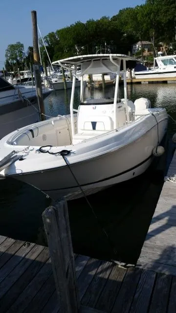 Slide: The Image of 2016 Wellcraft 252 Fisherman boat docked in a marina, surrounded by other vessels. - 2