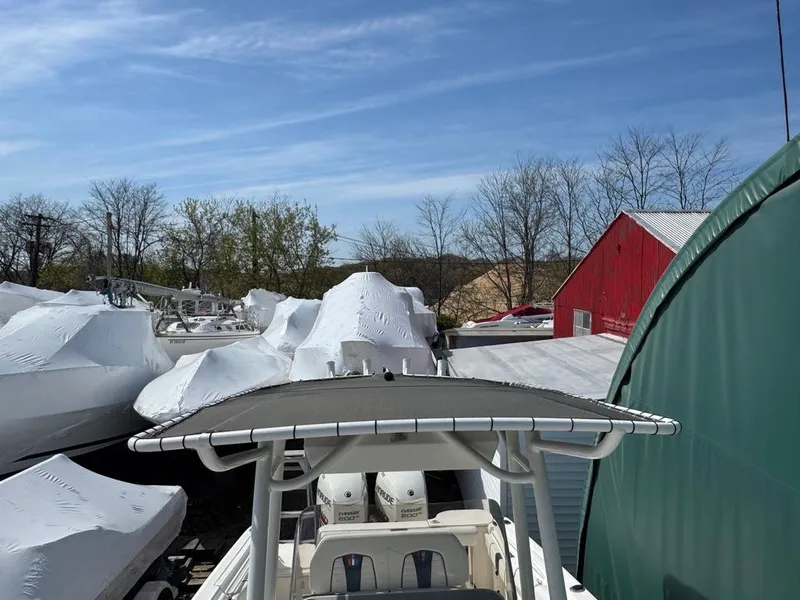 Slide: The Image of 2016 Wellcraft 252 Fisherman boat stored outdoors, surrounded by covered boats and a red barn. - 22