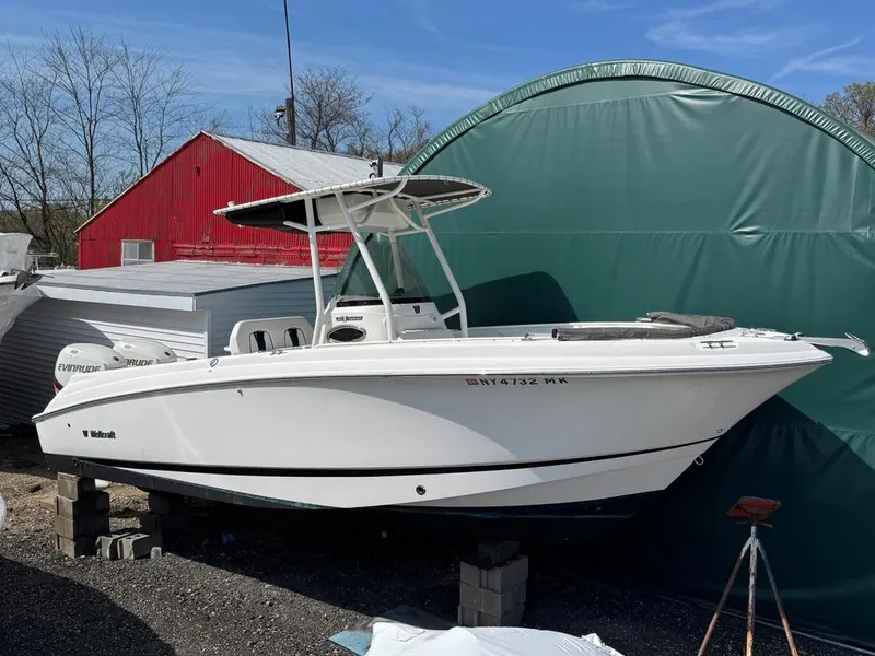 Slide: The Image of 2016 Wellcraft 252 Fisherman boat on blocks, near red and green buildings. - 3