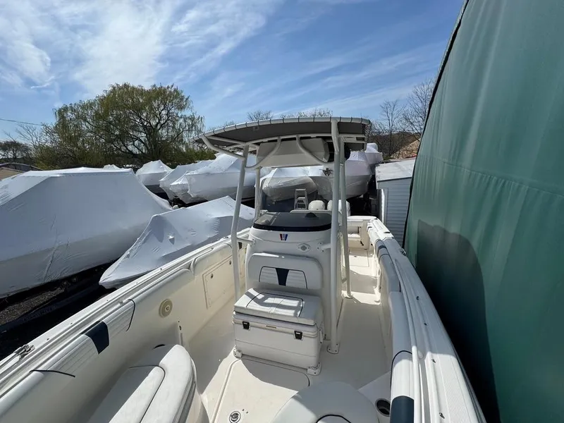 Slide: The Image of 2016 Wellcraft 252 Fisherman boat docked, featuring a center console and T-top under a clear sky. - 5