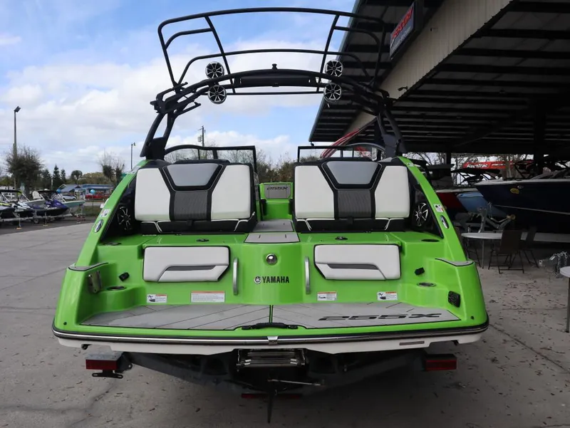 Slide: The Image of 2022 Yamaha Boats 255XD in vibrant green, rear view at a marina. - 4
