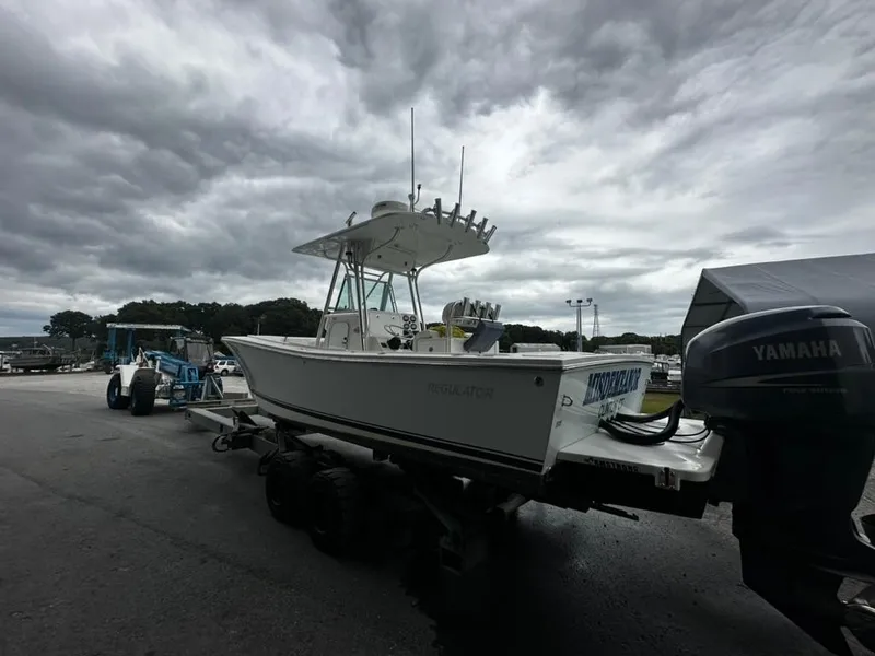 Slide: The Image of 2005 Regulator 26 FS boat on trailer with Yamaha outboard, under cloudy sky. - 2