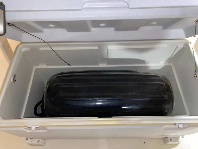 Slide: The Image of Open cooler with a black object inside, on a 2011 Scout 222 Sportfish boat. - 46