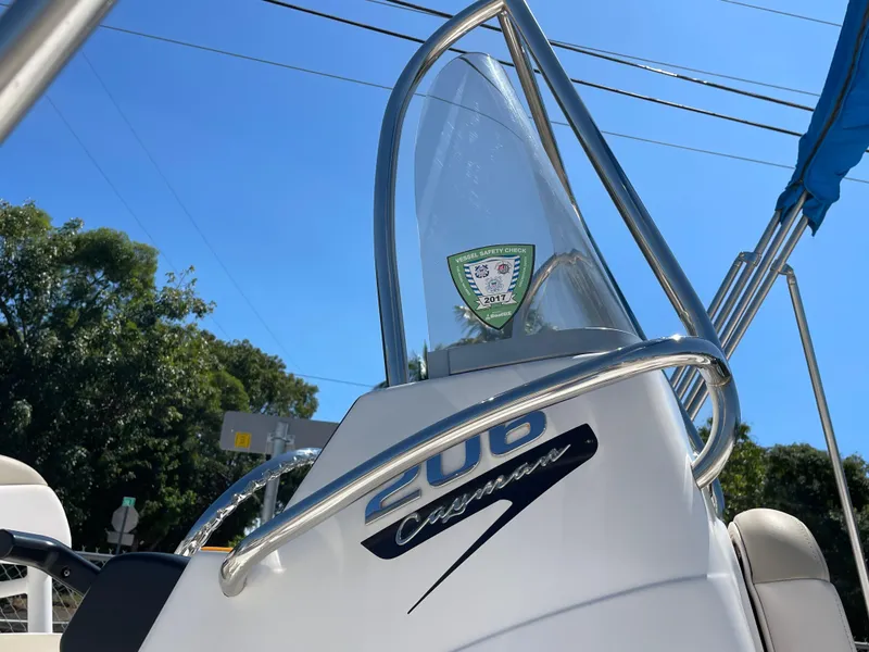 Slide: The Image of 2017 Robalo 206 Cayman boat console with clear windshield and logo, under blue sky. - 4