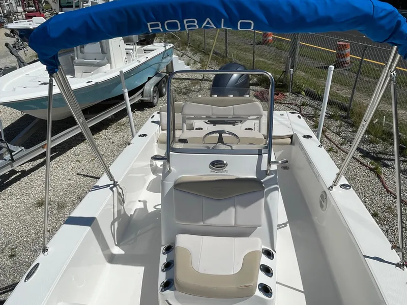 Slide: The Image of 2017 Robalo 206 Cayman boat with blue canopy and beige seating, docked outdoors. - 7
