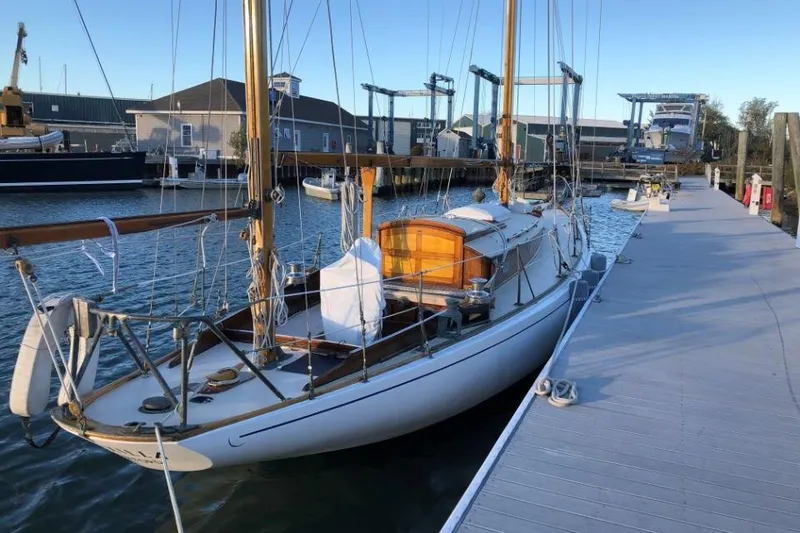 Slide: The Image of 1952 Concordia Yawl docked at marina, showcasing classic wooden design. - 2