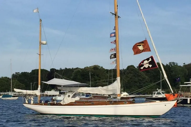 Slide: The Image of 1952 Concordia Yawl sailboat with pirate flags on a calm water backdrop. - 8