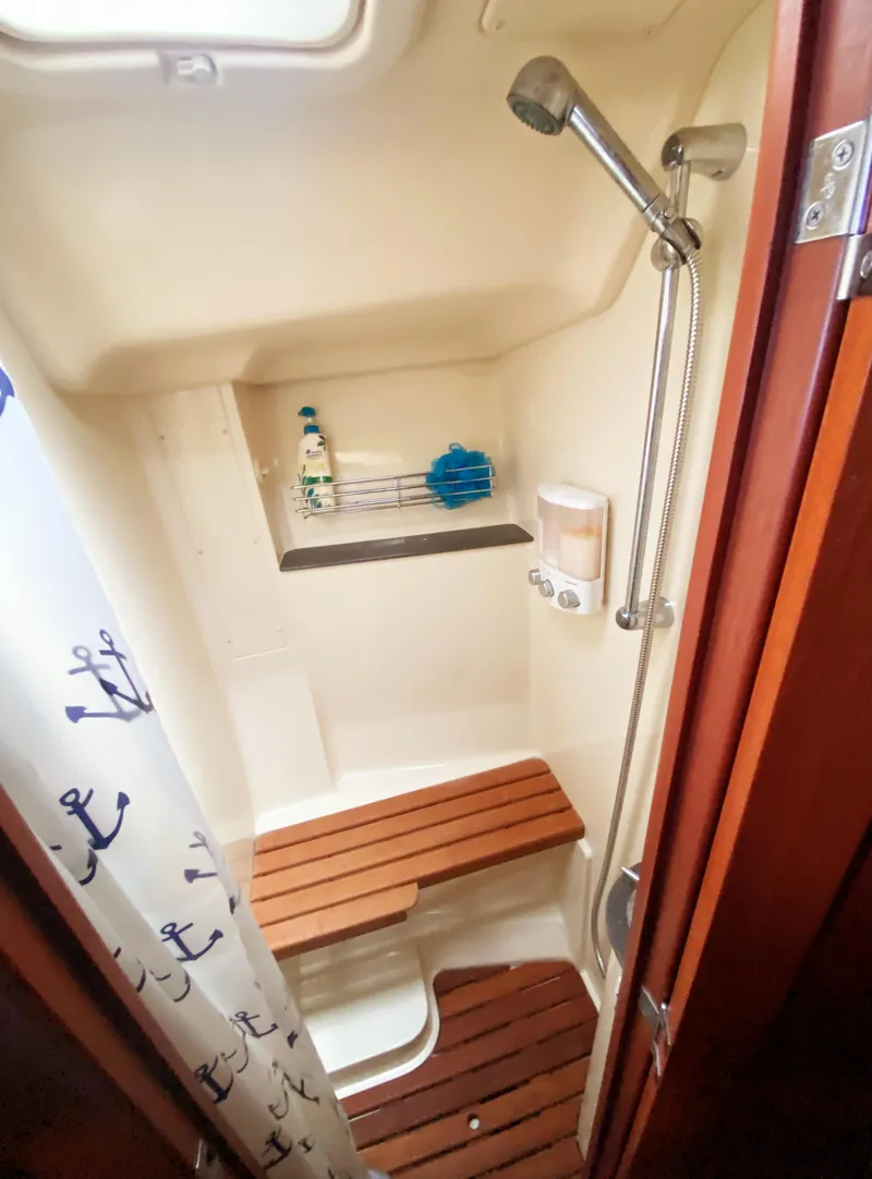 Slide: The Image of Shower area in 2012 Hunter 50 Aft Cockpit yacht with wooden seating and nautical-themed curtain. - 24