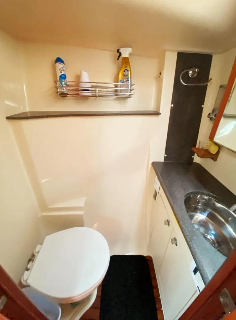 Slide: The Image of 2012 Hunter 50 Aft Cockpit bathroom with toilet, sink, and storage shelf. - 27