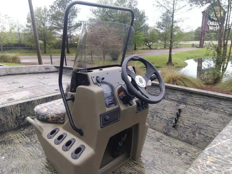 Slide: The Image of 2025 Tracker Grizzly 2072 CC boat console with steering wheel and windshield, outdoors setting. - 11