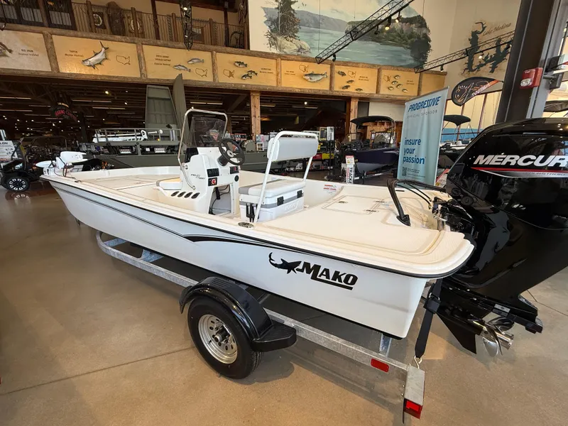 Slide: The Image of 2025 Mako Pro Skiff 17 CC boat displayed indoors on a trailer. - 2